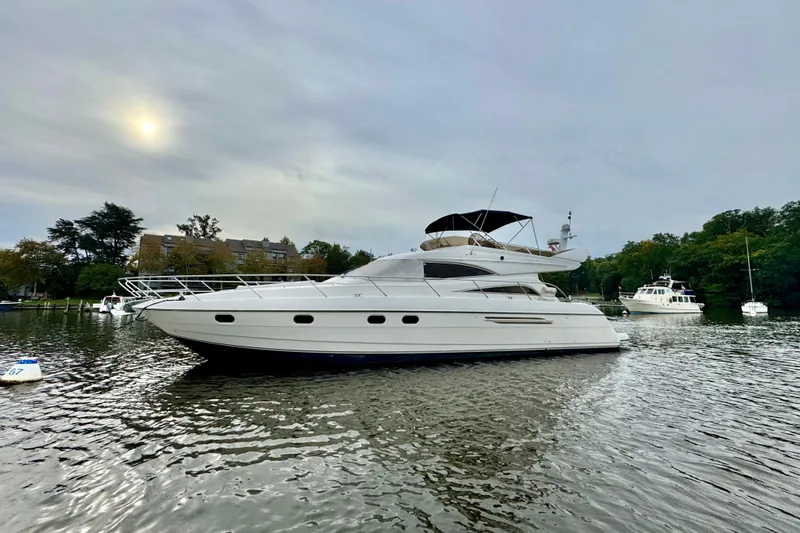  Yacht Photos Pics 1999 Viking Princess 56 yacht on calm water, overcast sky, surrounded by trees and buildings.