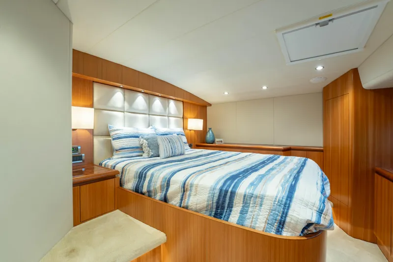 Vitality Yacht Photos Pics Luxurious bedroom interior on 2016 Horizon PC60 yacht with striped bedding and wood paneling.