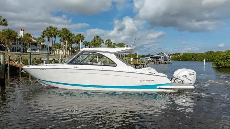  Yacht Photos Pics 2022 Regal LX36 boat cruising on a scenic waterway with palm trees and cloudy sky.