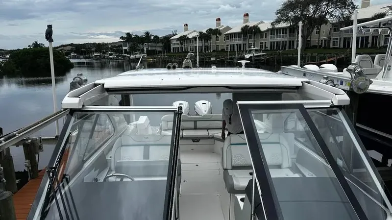  Yacht Photos Pics 2022 Regal LX36 boat docked near waterfront homes under cloudy skies.