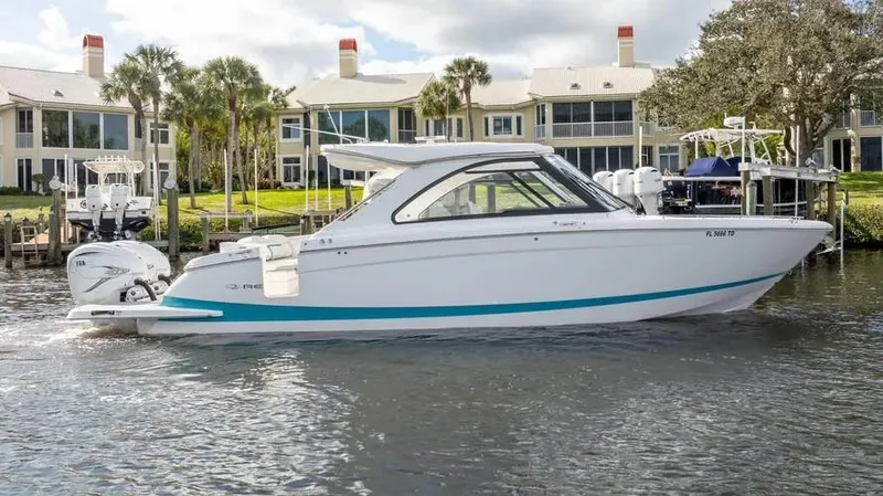  Yacht Photos Pics 2022 Regal LX36 boat cruising on a scenic waterfront with modern homes in the background.