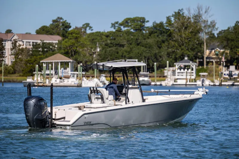  Yacht Photos Pics 2023 Pathfinder 2700 Open boat cruising on a scenic waterway near docks and trees.