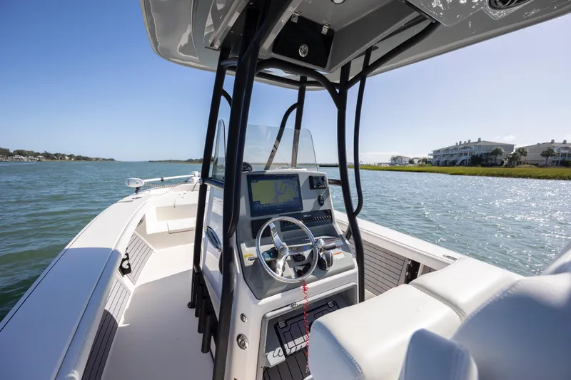  Yacht Photos Pics 2023 Pathfinder 2700 Open boat interior with steering wheel and navigation system on calm water.