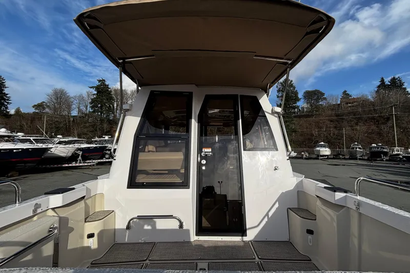  Yacht Photos Pics 2026 Ranger Tugs R-23 boat with canopy, docked in a marina under a blue sky.