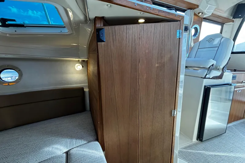  Yacht Photos Pics 2026 Ranger Tugs R-23 interior with seating, wooden cabinetry, and compact fridge.