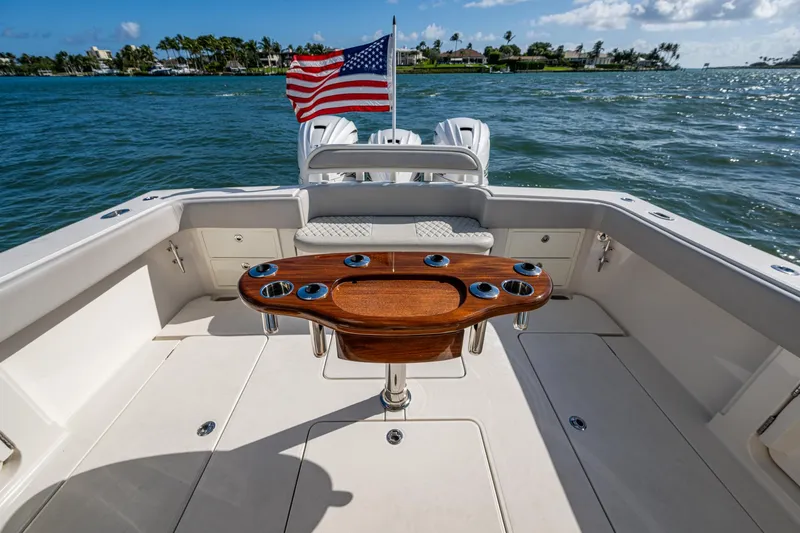 Seas The Day Yacht Photos Pics 2020 Jupiter 43 boat deck with American flag, ocean view, and wooden table.