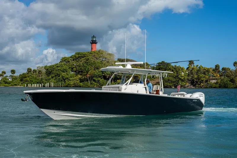 Seas The Day Yacht Photos Pics 2020 Jupiter 43 boat cruising near a scenic lighthouse and lush greenery.