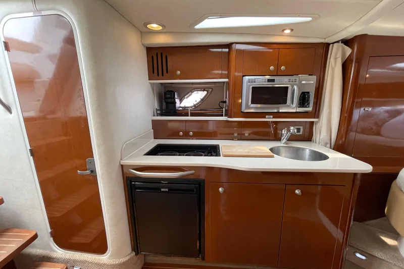 Catalyst Yacht Photos Pics 2009 Sea Ray 330 Sundancer kitchen with microwave, sink, and stove in wooden cabinetry.