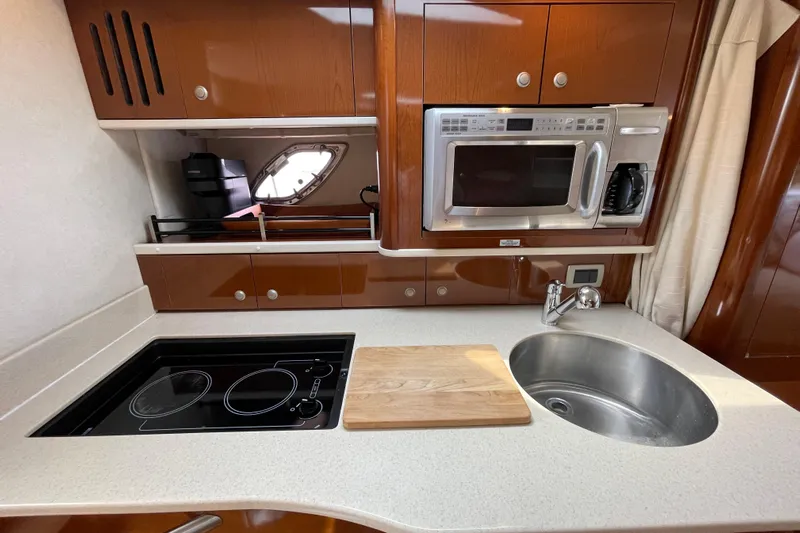 Catalyst Yacht Photos Pics 2009 Sea Ray 330 Sundancer kitchen with stove, microwave, sink, and wooden cutting board.