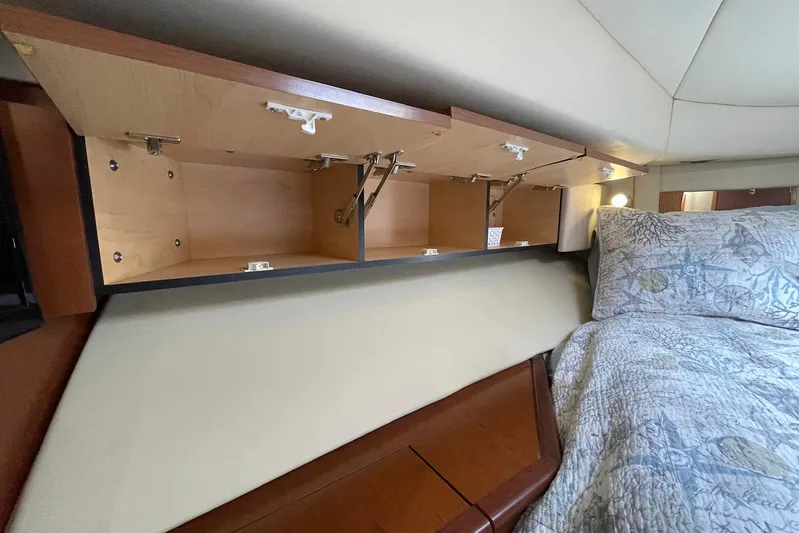 Still Waters Yacht Photos Pics 2007 Sea Ray 44 Sedan Bridge interior with open wooden cabinets above a bed.