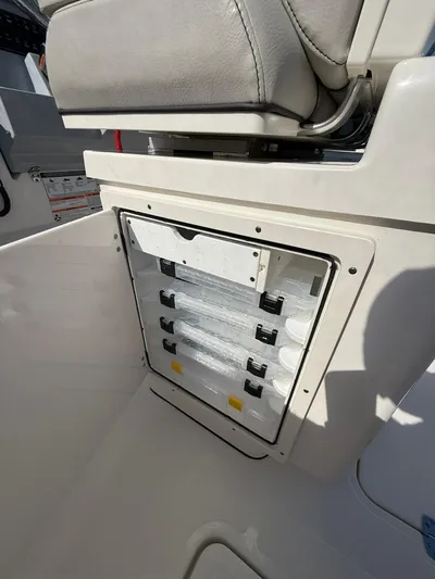  Yacht Photos Pics 2023 Pursuit S 268 Sport boat storage compartment with tackle trays and cushioned seat.