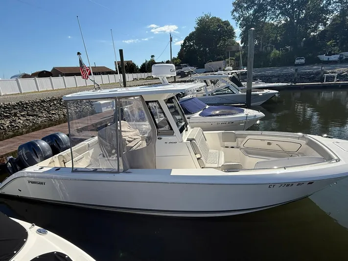  Yacht Photos Pics 2023 Pursuit S 268 Sport boat docked in a marina under clear skies.