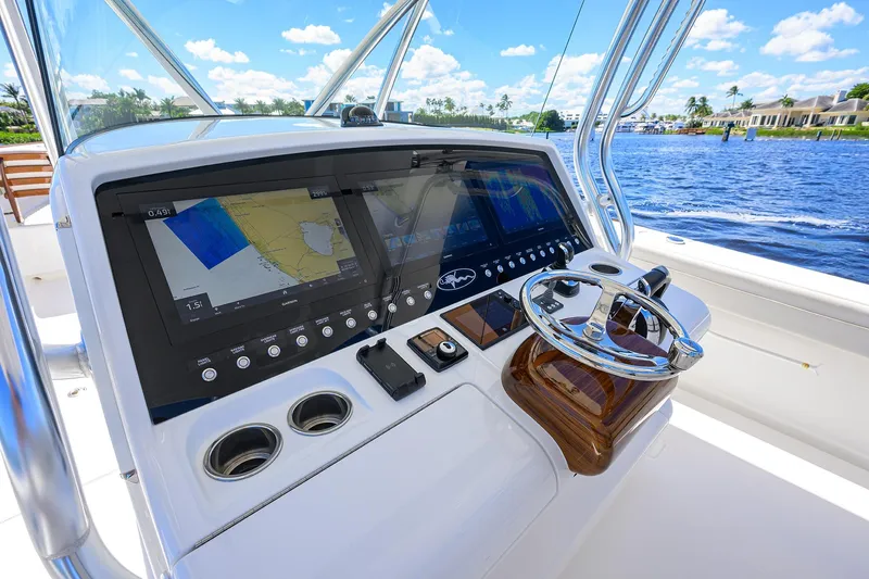 Miss Allied Yacht Photos Pics 2022 Valhalla V41 boat dashboard with navigation screens and steering wheel, overlooking a scenic waterway.