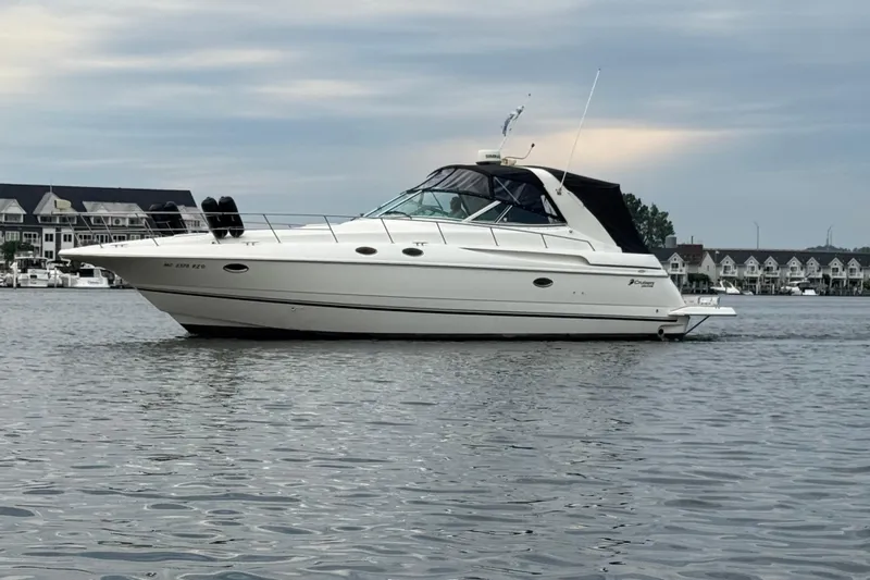 Lubb Shack Yacht Photos Pics 2000 Cruisers Yachts 3870 Express on calm water, with waterfront homes in the background.