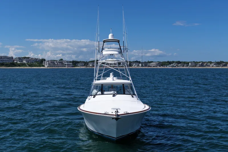 Pamela Yacht Photos Pics 2024 Viking 48 Sport Tower yacht on open water, coastal town in background.