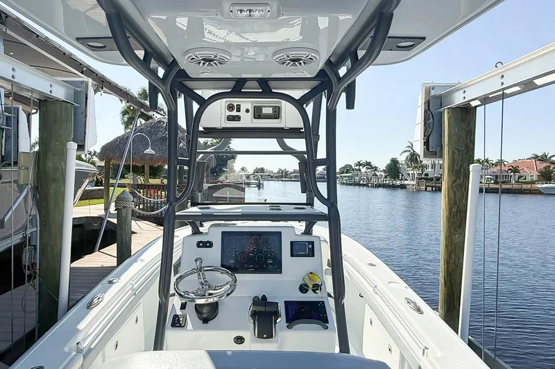  Yacht Photos Pics 2022 Yellowfin 26 Hybrid boat interior with steering console, docked by a scenic waterfront.