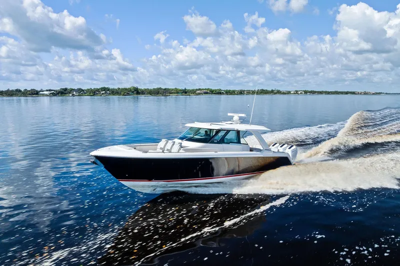 Moonrunner Yacht Photos Pics 2024 Tiara Yachts 48 LS cruising on a calm, scenic waterway under a partly cloudy sky.