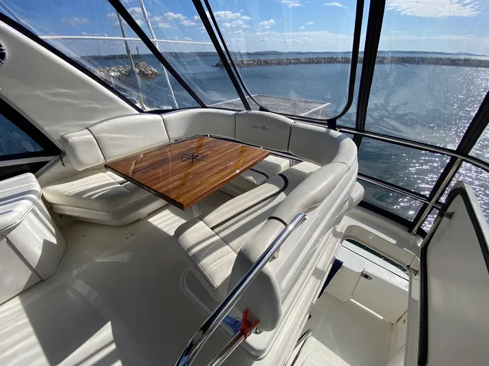  Yacht Photos Pics 2005 Sea Ray 420 Sedan Bridge interior with white seating and wooden table, overlooking the ocean.