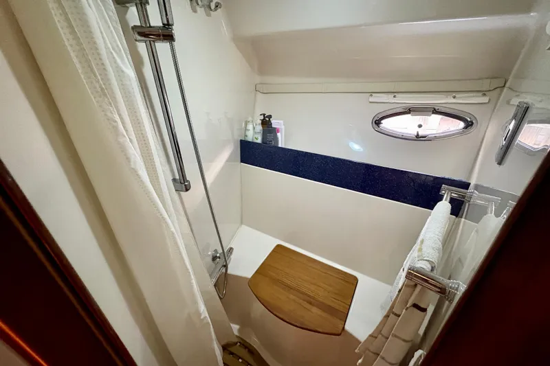 Outstanding Yacht Photos Pics Compact bathroom in 2007 Doral Alegria boat with shower, wooden seat, and porthole window.