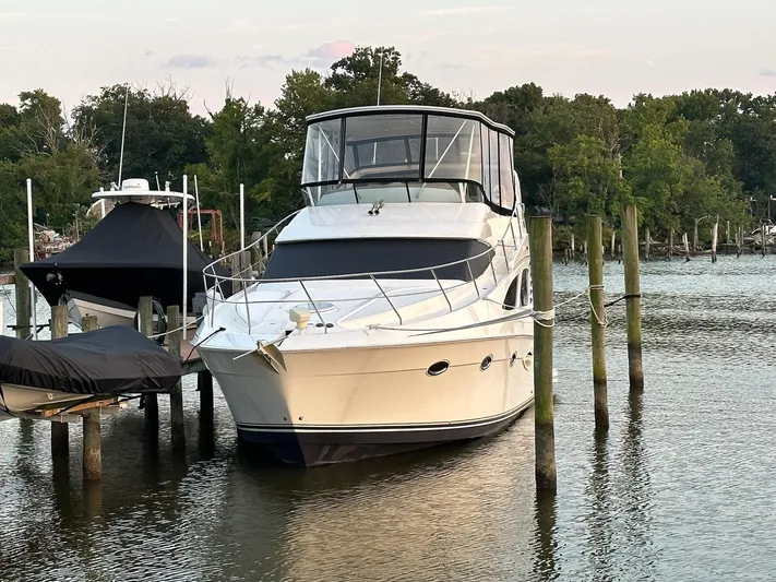  Yacht Photos Pics 2005 Silverton 38 Sport Bridge yacht docked on a serene lake with lush greenery.
