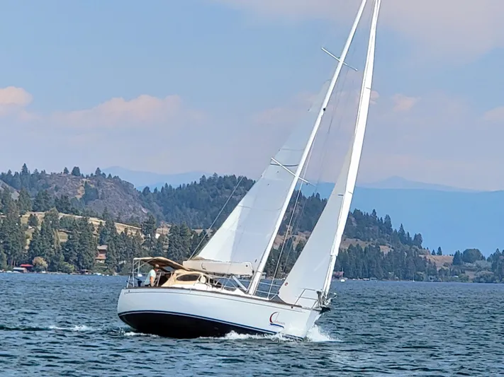 Celebration Yacht Photos Pics Sailboat Tartan 3400 (2007) cruising on a scenic lake with forested hills.