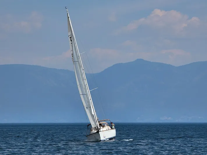 Celebration Yacht Photos Pics Sailboat Tartan 3400 (2007) navigating on a serene lake with mountainous backdrop.