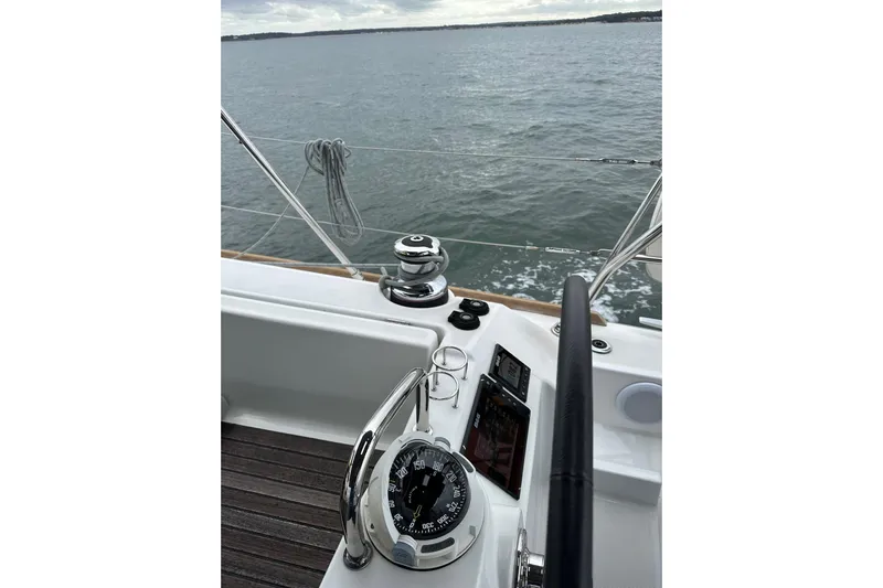  Yacht Photos Pics Steering wheel and compass on 2017 Beneteau Oceanis 45 sailboat, overlooking calm waters.