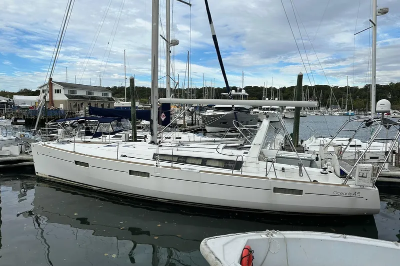  Yacht Photos Pics 2017 Beneteau Oceanis 45 sailboat docked at a marina under a cloudy sky.
