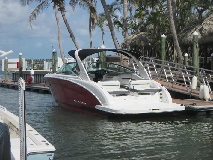  Yacht Photos Pics 2017 Regal 3200 Bowrider docked near palm trees, showcasing sleek design and spacious seating.