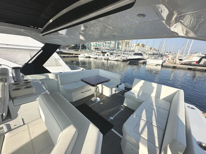 Lux Life Yacht Photos Pics 2017 Cruisers Yachts 390 Express Coupe interior with marina view, featuring sleek seating and table.