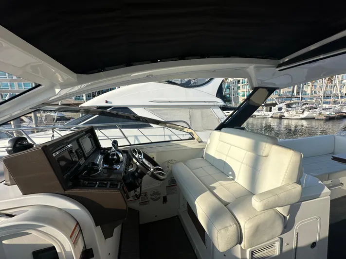Lux Life Yacht Photos Pics 2017 Cruisers Yachts 390 Express Coupe interior with helm and seating, docked at marina.