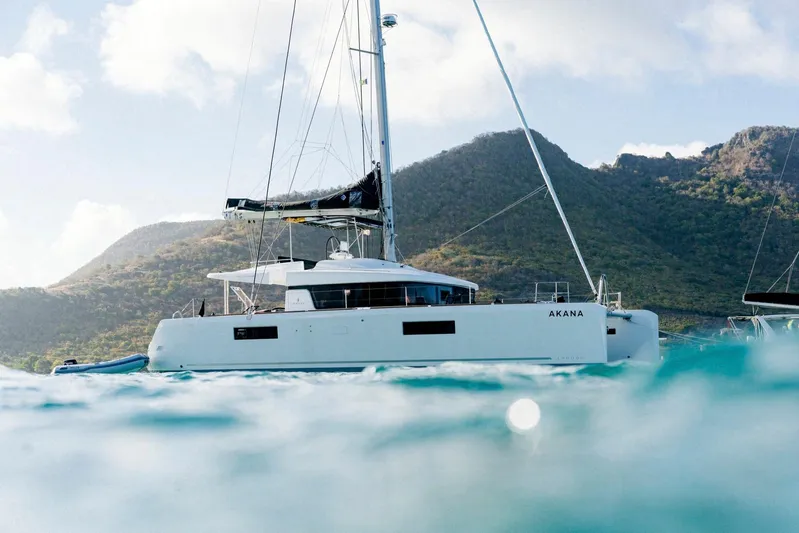  Yacht Photos Pics 2019 Lagoon 52 F catamaran sailing near scenic mountains and clear blue water.