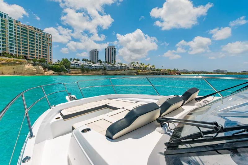  Yacht Photos Pics 2025 Jeanneau Cap Camarat 12.5 WA cruising near coastal buildings under a bright blue sky.