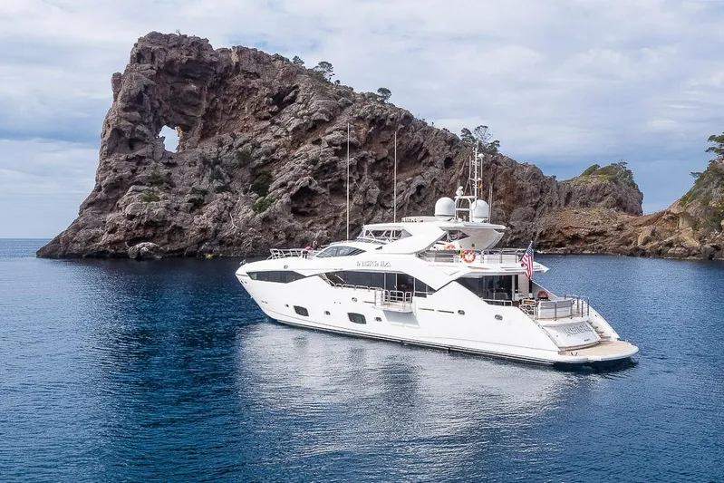 Insignia Yacht Photos Pics Luxurious 2015 Sunseeker 115 yacht anchored near a rocky coastal formation.