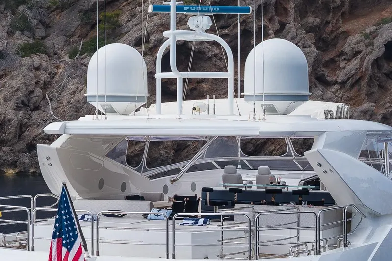Insignia Yacht Photos Pics Luxury Sunseeker 115 yacht, 2015 model, with American flag, docked near rocky coastline.