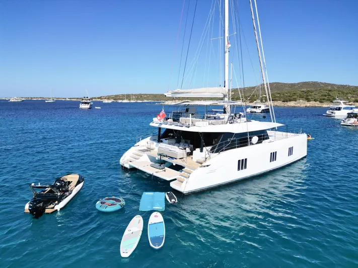 Dawn Yacht Photos Pics 2019 Sunreef 60 catamaran anchored with paddleboards and jet ski in clear blue water.