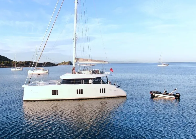 Dawn Yacht Photos Pics 2019 Sunreef 60 yacht anchored in serene waters with a small boat nearby.