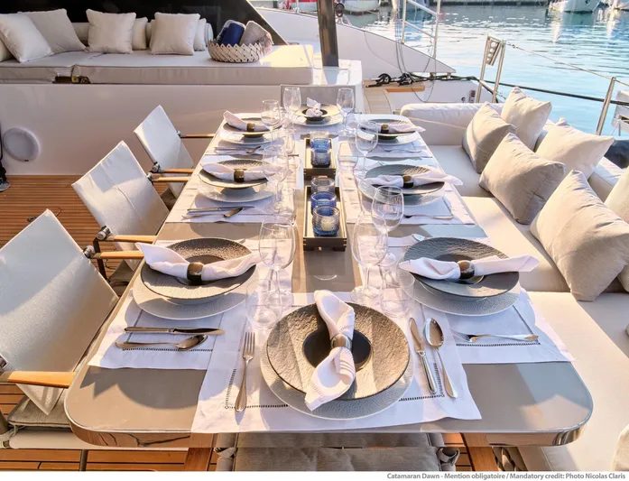 Dawn Yacht Photos Pics Elegant dining setup on 2019 Sunreef 60 yacht, featuring stylish tableware and comfortable seating.
