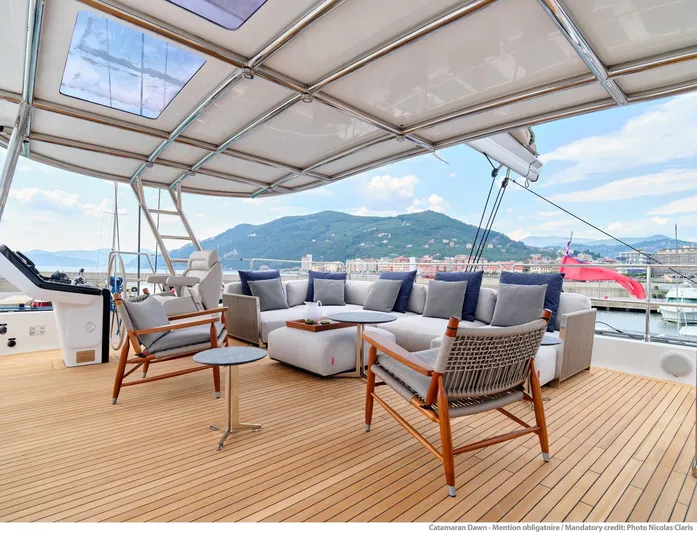 Dawn Yacht Photos Pics Luxurious Sunreef 60 yacht deck with elegant seating, 2019 model, scenic coastal view.