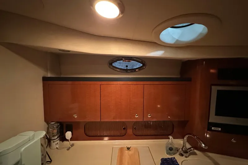  Yacht Photos Pics 2004 Sea Ray 340 Sundancer cabin interior with wooden cabinets and porthole window.