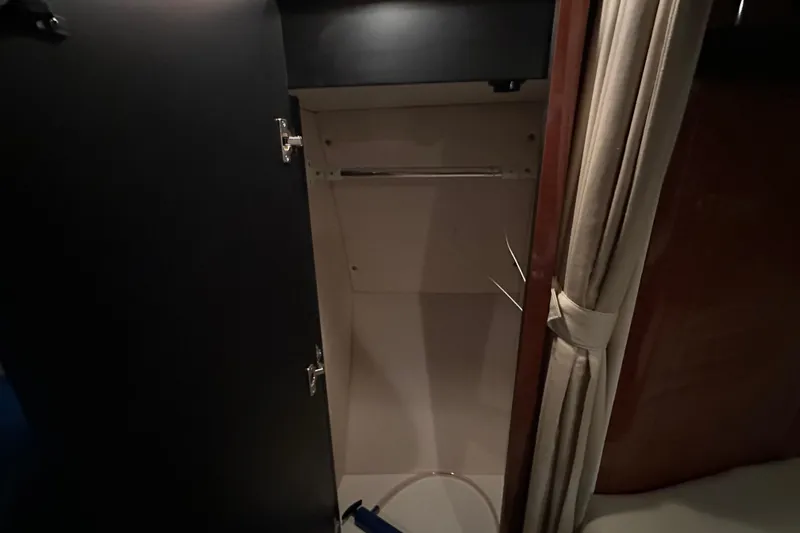  Yacht Photos Pics Open closet inside 2004 Sea Ray 340 Sundancer boat cabin, featuring dark wood and curtain.