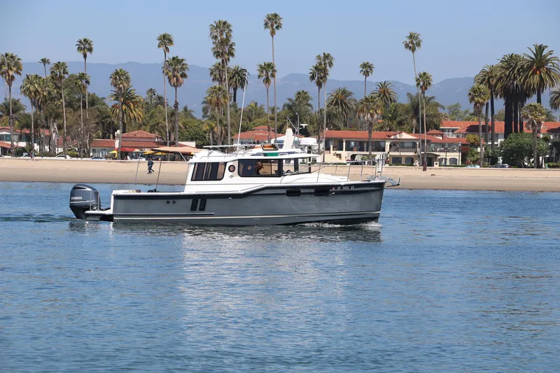  Yacht Photos Pics 2020 Ranger Tugs R-27 boat cruising near a scenic beach with palm trees.