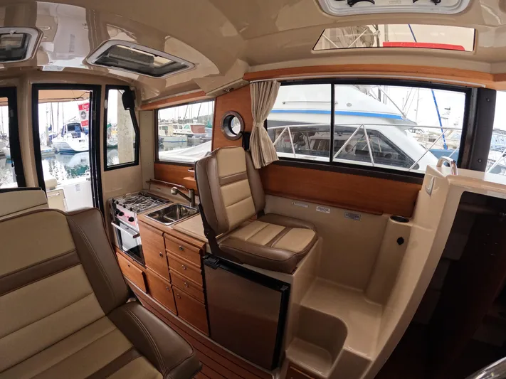  Yacht Photos Pics Interior of 2020 Ranger Tugs R-27 boat with seating, kitchenette, and windows.