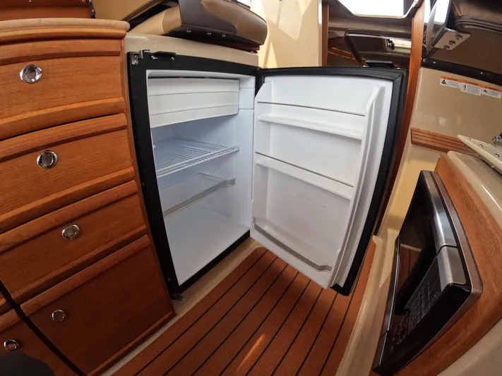  Yacht Photos Pics 2020 Ranger Tugs R-27 interior with open refrigerator, wooden cabinetry, and flooring.