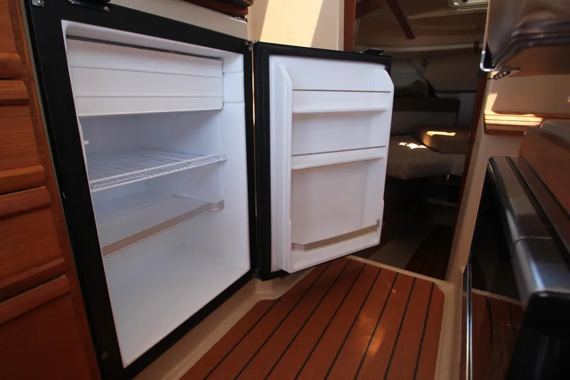  Yacht Photos Pics 2020 Ranger Tugs R-27 interior with open refrigerator, showcasing wooden flooring and cabin space.