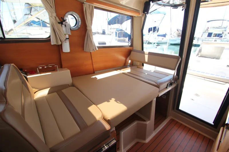  Yacht Photos Pics 2020 Ranger Tugs R-27 interior with convertible seating and wood accents in a marina setting.