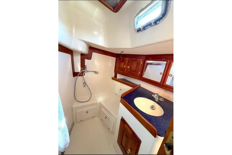 R'liberty Yacht Photos Pics 2001 Tartan 3700 yacht bathroom with shower, sink, and wooden cabinetry.