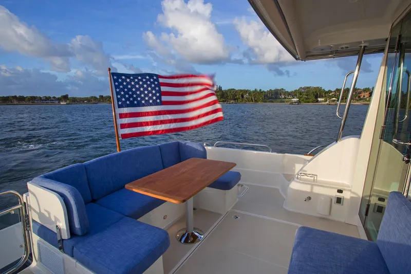  Yacht Photos Pics 2025 Sabre 45 Salon Express yacht with American flag, blue seating, and wooden table on deck.