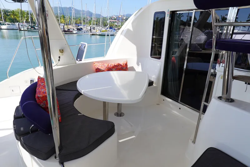  Yacht Photos Pics Leopard 40 catamaran cockpit with seating, table, and colorful cushions, docked in a marina.