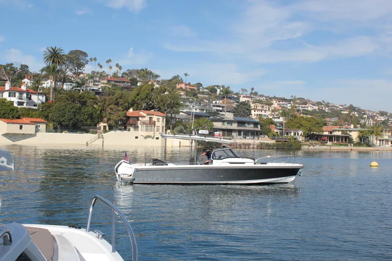 San #155 In Stock Yacht Photos Pics 2024 Nimbus T9 boat cruising near a scenic coastal town with hillside homes.